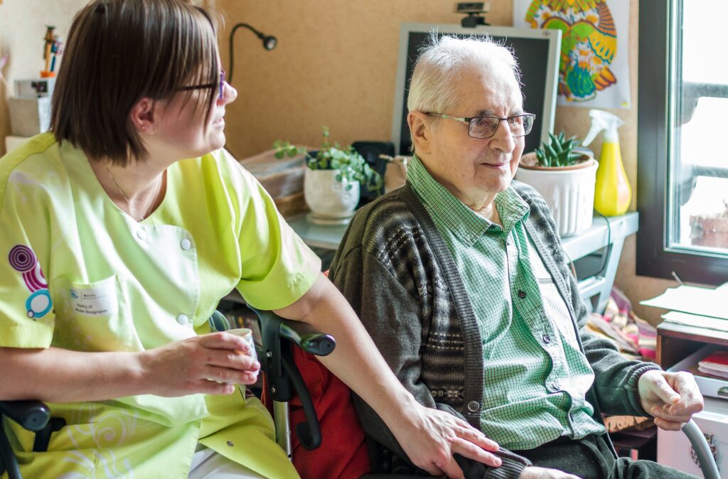 Une professionnelle de la Maison Saint-Louis assise auprès d'un résident